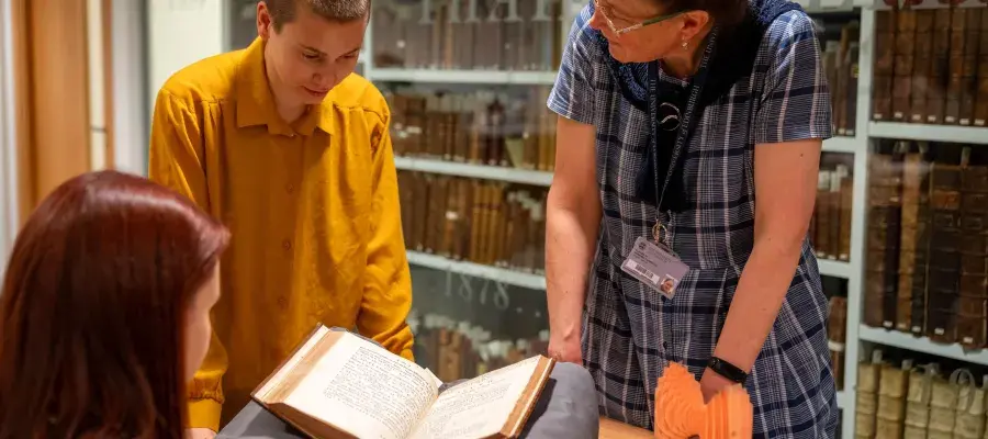This image shows students and curator discussing a book.
