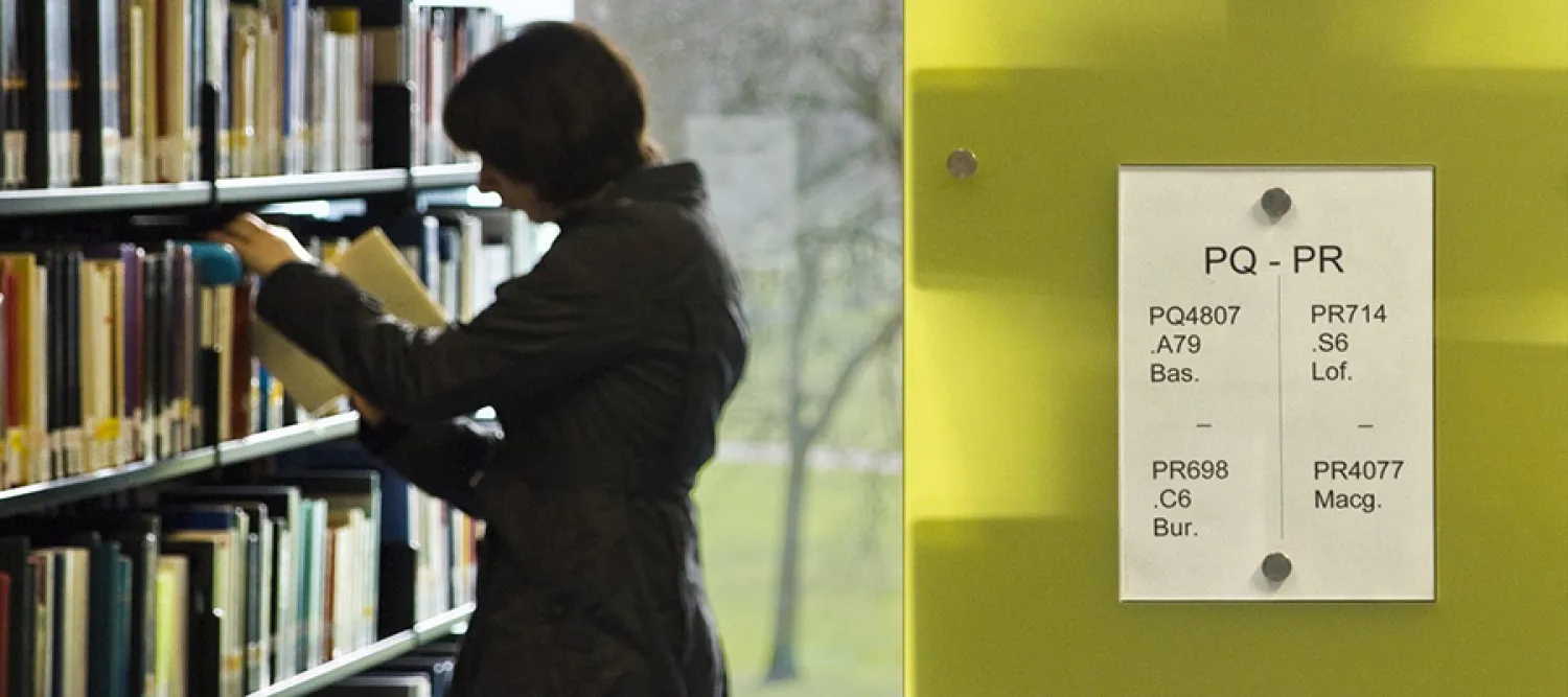 Person selecting book on a library bookshelf 