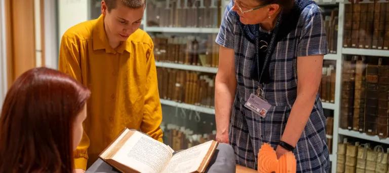 This image shows students and curator discussing a book.