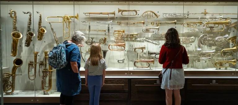 Three people looking at musical instruments in St Cecilia's Hall