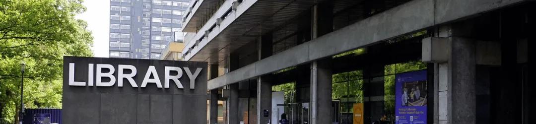 A photograph of the Main Library, with the Library sign to the left and the front entrance to the right.