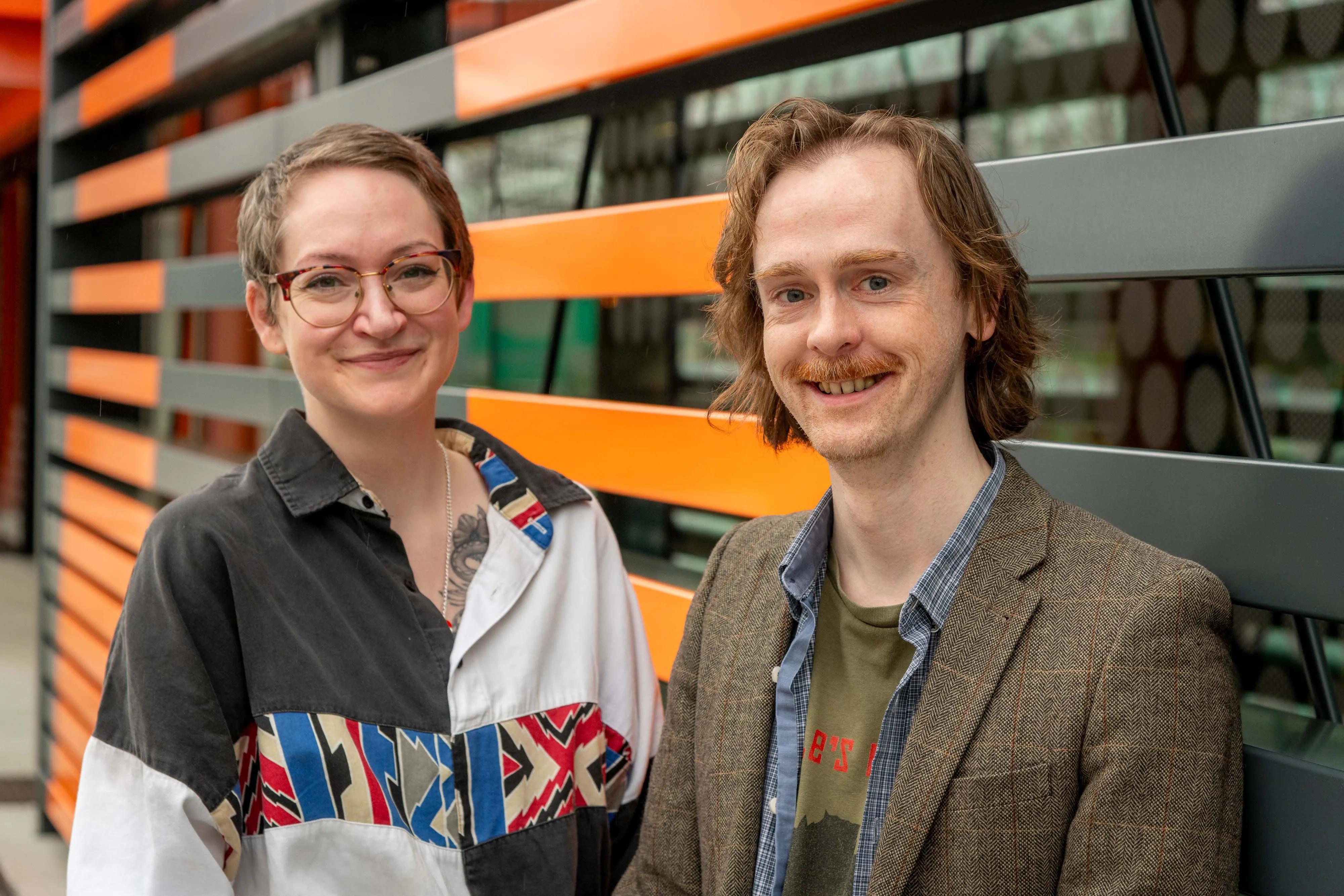 Rebecca Wojturska (with short brown hair, glasses and a black and white shirt) and Simon Bowie (with medium length brown hair, a moustache, and a tweed suit jacket).).