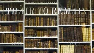Clement Littil quote ‘Thair to Remain’ on glass in with Adam Smith Library in the background, Treasures Room, 2011, Centre for Research Collections, Main Library